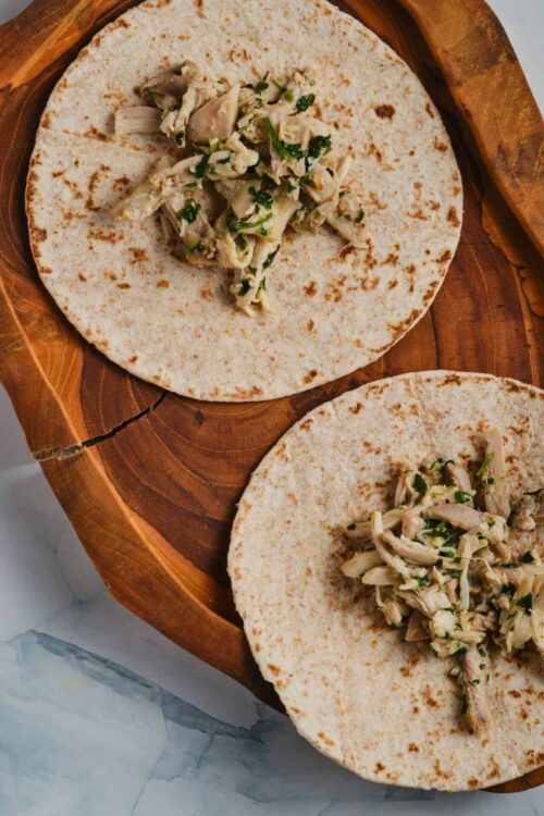 Savory shredded chicken tacos on flour tortillas with fresh herbs.