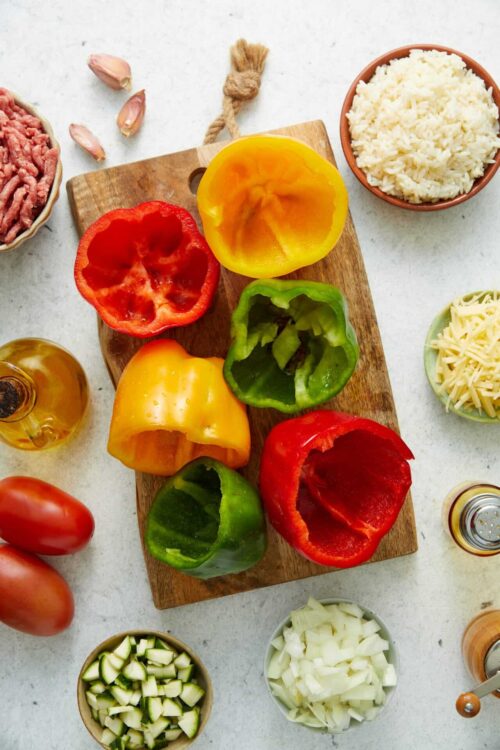 Colorful bell peppers on wooden cutting board for stuffing or cooking.