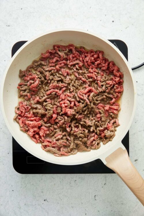 Mince beef browning in a white skillet for cooking recipes.
