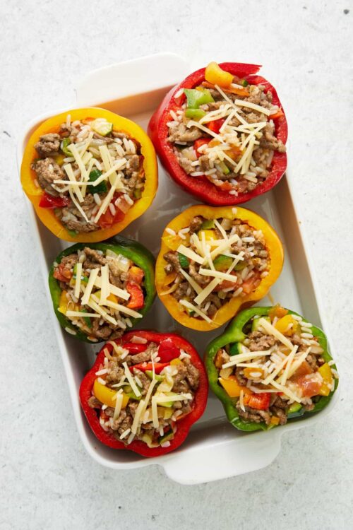 Colorful stuffed bell peppers with ground meat, rice, vegetables, and cheese baked in red, yellow, and green peppers.