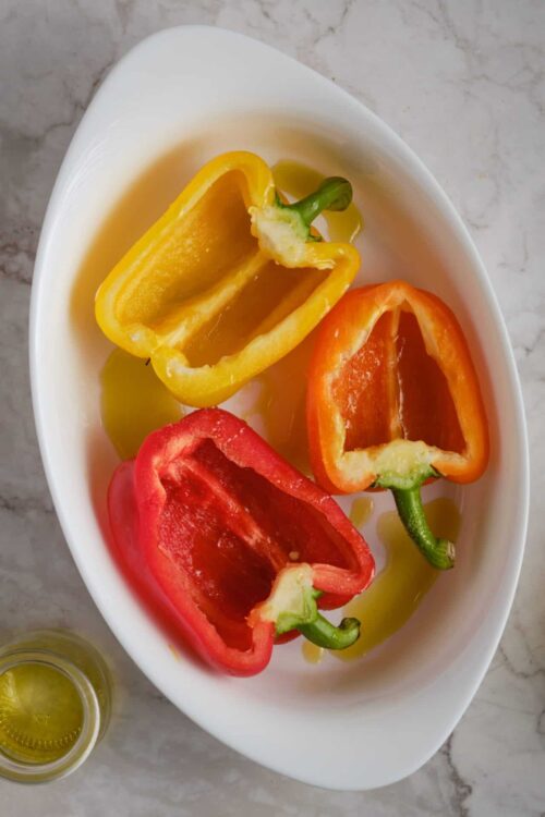 Colorful stuffed bell peppers in yellow, orange, and red, sliced open on a white platter.