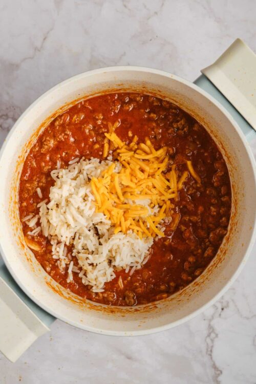 Creamy taco pasta with seasoned ground beef, shredded cheddar and mozzarella cheese in a white pot.