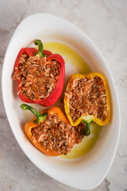 Colorful stuffed bell peppers filled with seasoned rice and ground meat on a white serving dish.