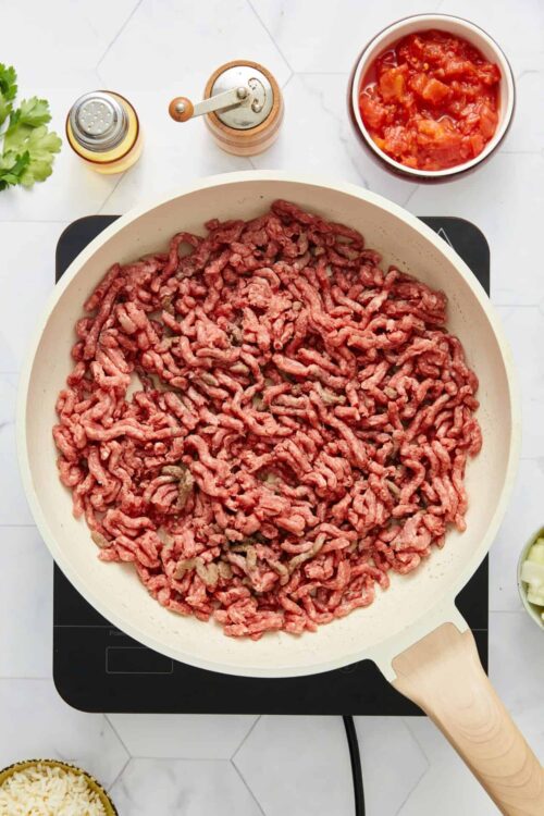 Cooked ground beef in a white skillet.