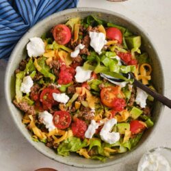 Cheeseburger salad in a bowl with fresh vegetables, ground beef, and toppings.