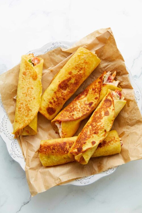 Golden crispy breakfast crepes filled with savory ingredients on decorative plate.