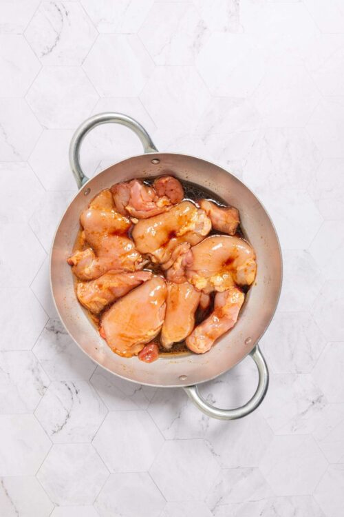 Boneless chicken thighs marinating in a skillet for flavorful cooking. Ideal for baking or stovetop recipes.