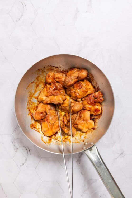Juicy cooked chicken thighs in a skillet with a flavorful sauce.
