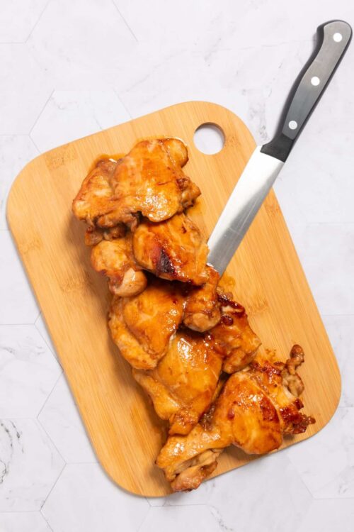 Crispy honey glazed chicken drumsticks on a wooden cutting board.