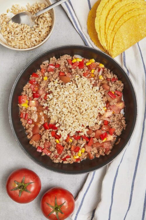Savory beef and rice skillet with vegetables and tomatoes, served with tortillas and cooked rice.