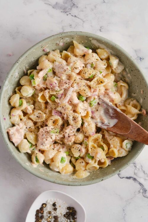 Creamy chicken and pasta salad with vegetables and herbs in a bowl.