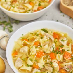 Comforting homemade chicken noodle soup with vegetables in a white bowl, perfect for fall and winter.