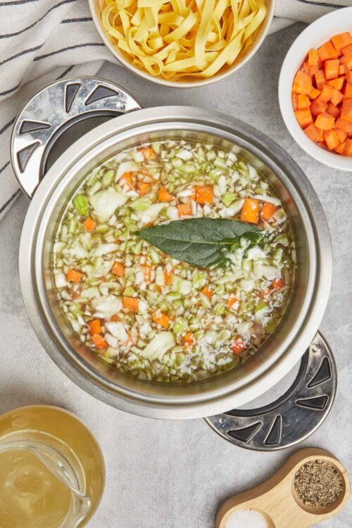 Vegetable soup with chopped carrots, celery, and onions in a slow cooker.