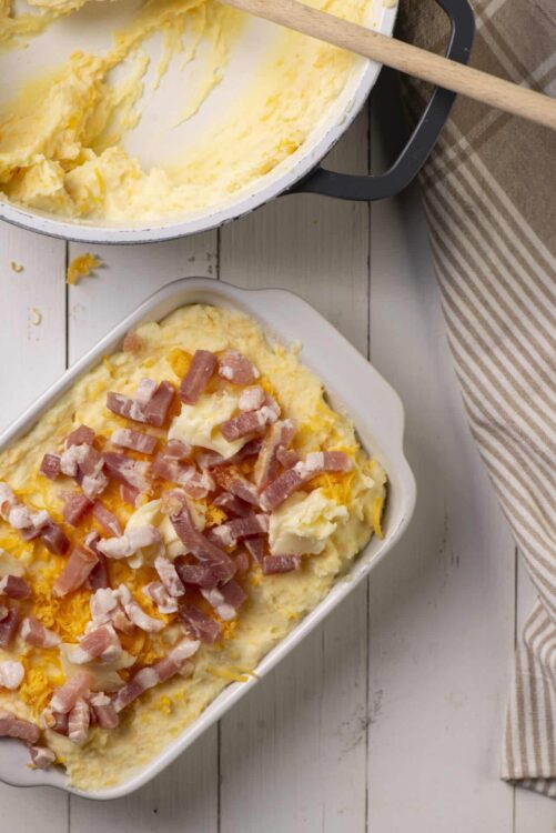 Creamy cheesy mashed potatoes with bacon in a baking dish, ready to bake or serve.