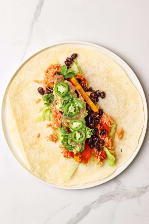 Fresh vegan black bean and vegetable taco ingredients on a white plate.
