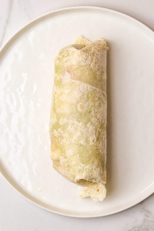 Cream cheese and spinach-filled burrito wrapped in flour tortilla, ready to be baked or served.