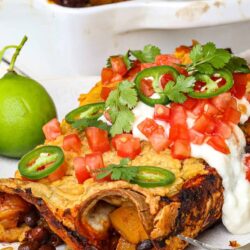 Savory stuffed poblano chili with beans, cheese, and fresh toppings on white plate.