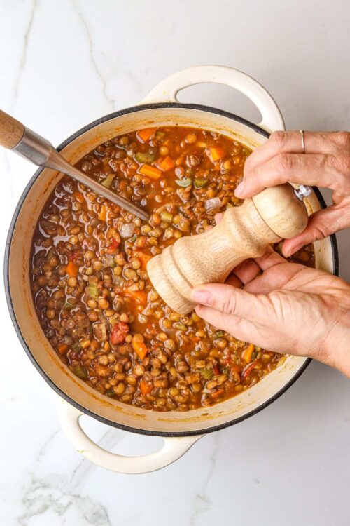 Hearty lentil soup with vegetables in a cast iron pot.