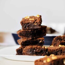 Rich, fudgy chocolate brownies with walnut toppings on a white plate, perfect for dessert or snacking.
