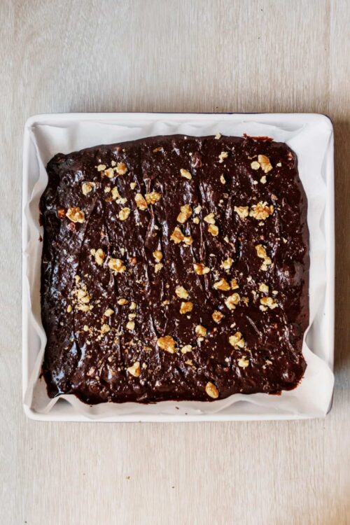 Rich chocolate sheet cake with walnuts on white parchment-lined baking dish.