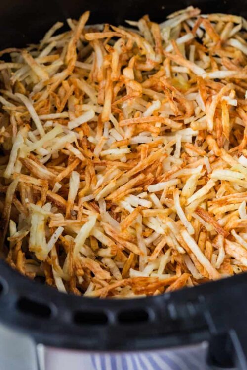 Crispy shredded hash browns in a black air fryer basket.