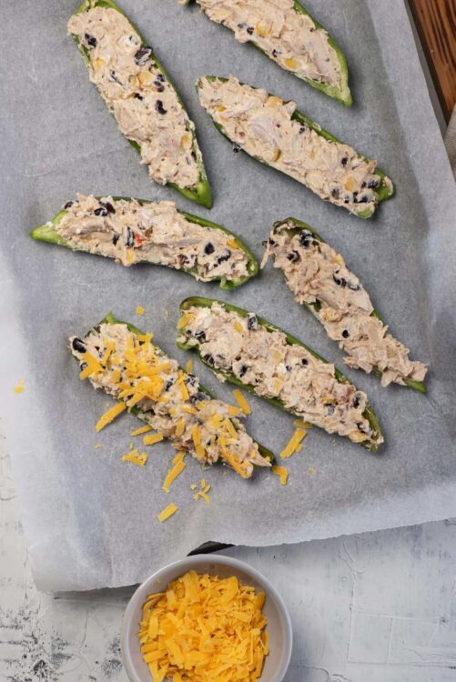 Cream cheese stuffed jalapeños with shredded cheddar cheese on top.