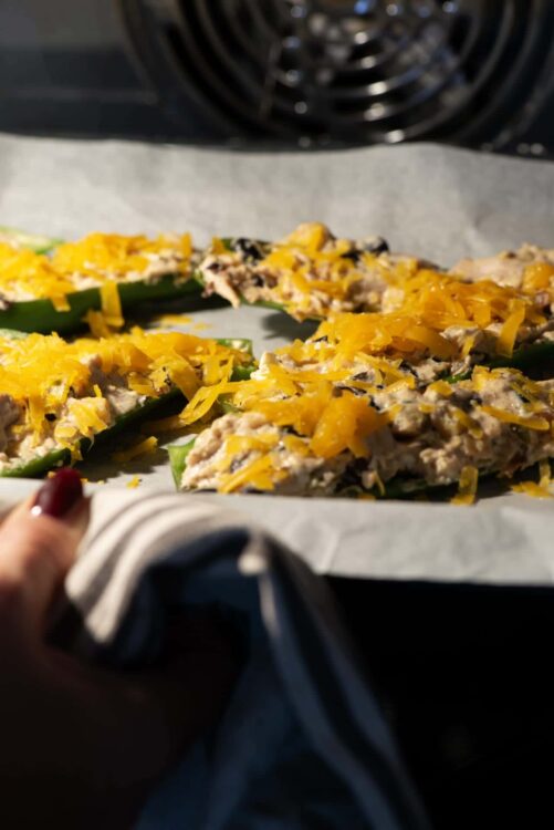 Baked stuffed zucchini boats topped with shredded cheddar cheese, ready to bake or serve.