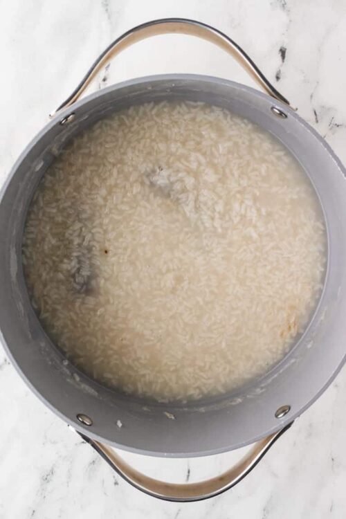 Steamed rice cooking in a stainless steel pot.