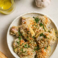 Crispy baked chicken drumsticks with garlic and herbs on a white oval plate. Perfect for easy, flavorful comfort food.