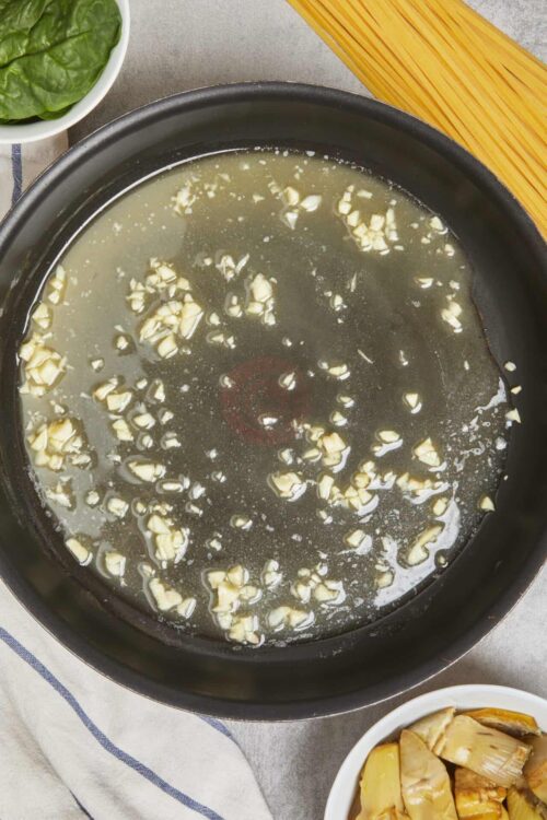 Minced garlic in hot olive oil on a skillet for cooking recipes.