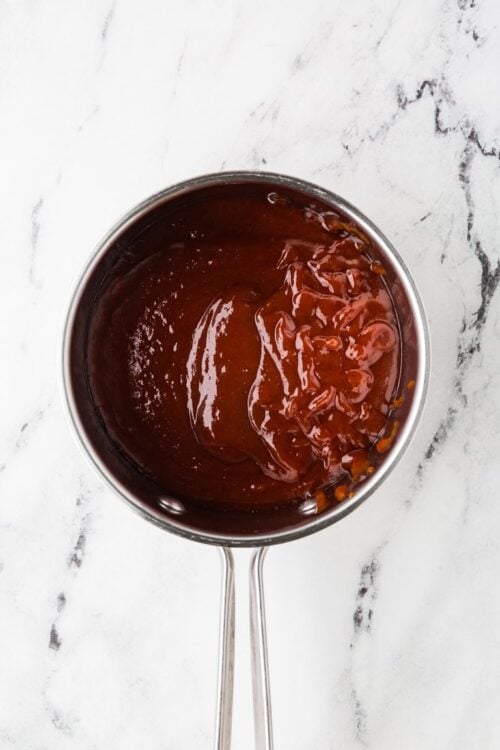Rich homemade barbecue sauce in a stainless steel saucepan.