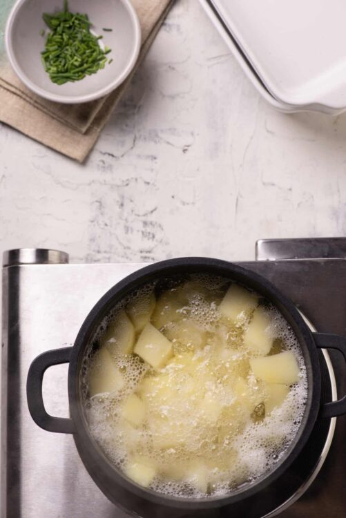 Boiling potatoes in a black pot for homemade recipes.