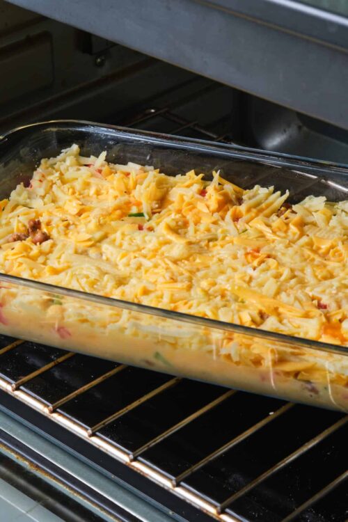 Creamy cheeseburger casserole baking in oven dish on oven rack.