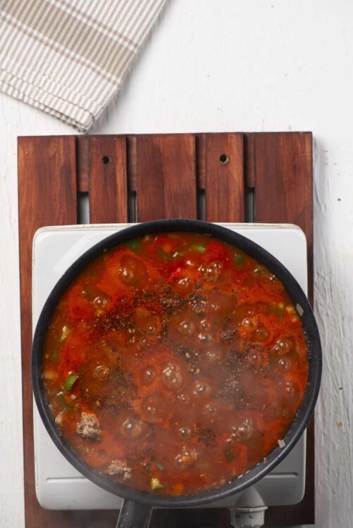 Chunky homemade tomato soup in a black skillet on a white stovetop.