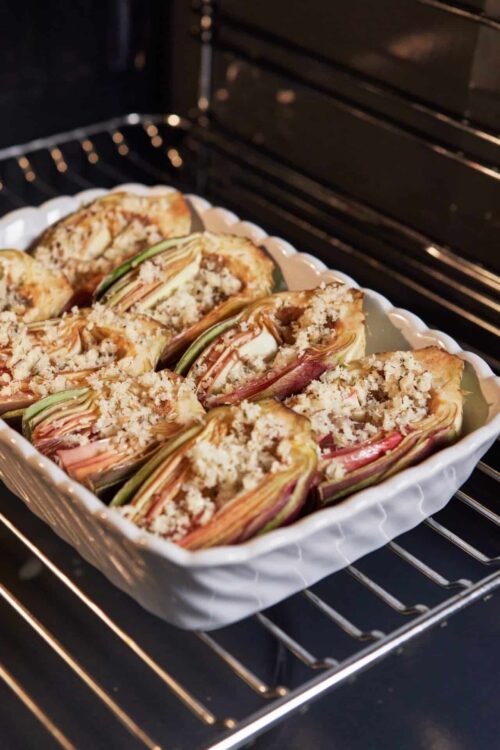 Baked Rabarbar Rolls with crumble topping in a white ceramic baking dish.
