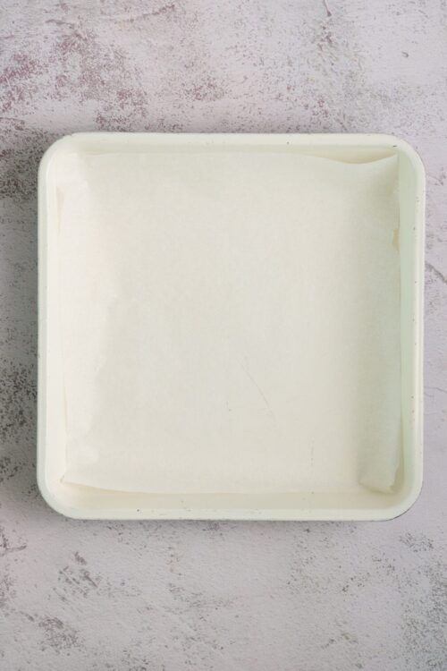 Unopened ice cream container with paper liner on a textured surface.