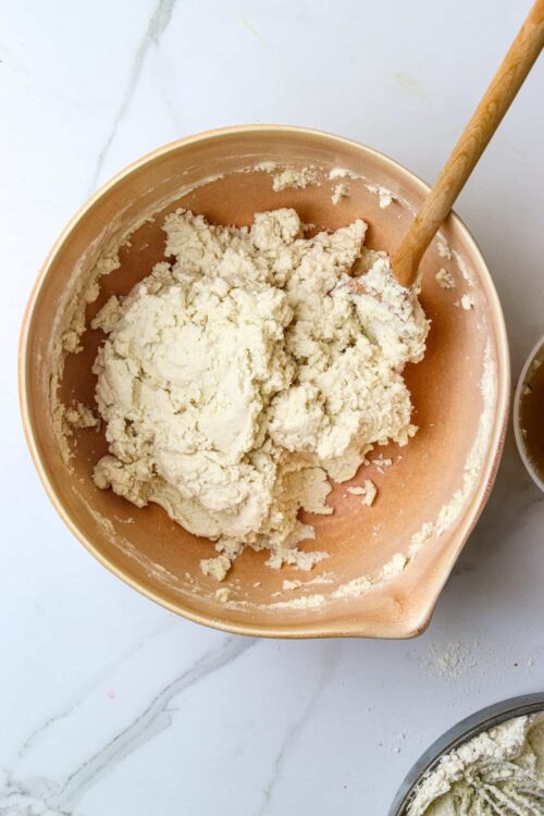 Crust dough in a mixing bowl with a wooden spoon for baked goods.
