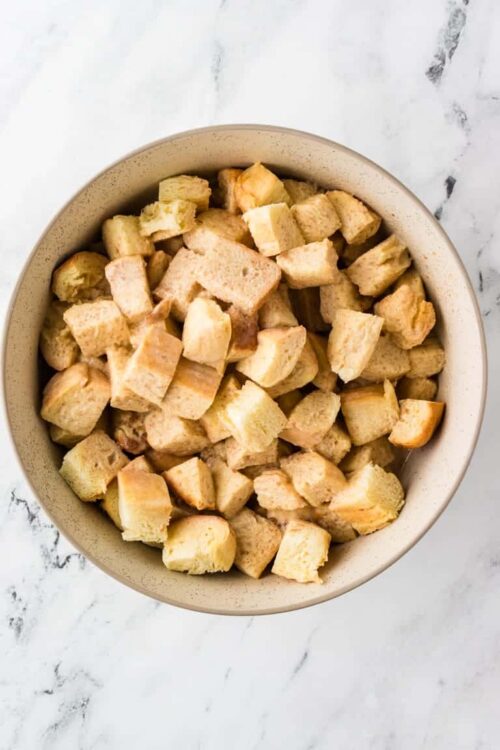 Cubed bread for stuffing or bread pudding in a beige bowl.