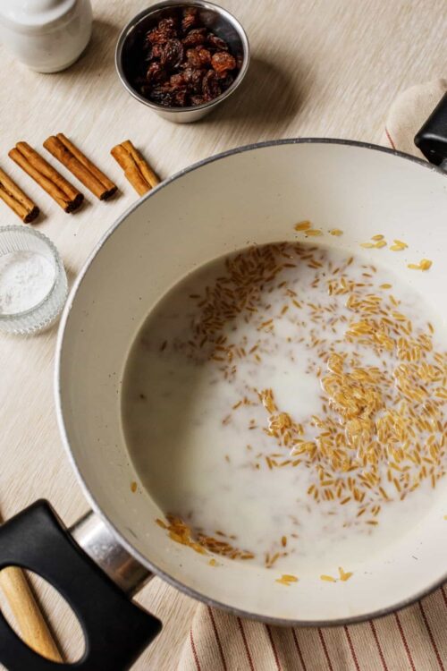 Golden brown orzo pasta cooking in a pot with milk for creamy pasta dish.