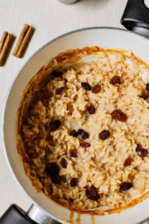 Creamy cinnamon raisin oatmeal in a white skillet.