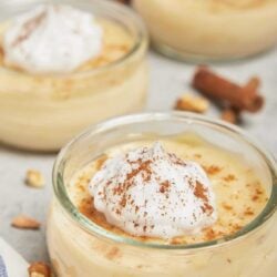 Creamy vanilla pudding topped with whipped cream and a sprinkle of cinnamon in glass bowls.