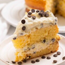 Cream cheese frosting with chocolate chips on a slice of classic vanilla cake.