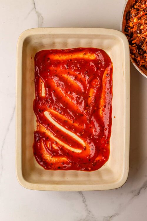 Creamy tomato sauce and cheese layers in a baking dish, ready for baking.