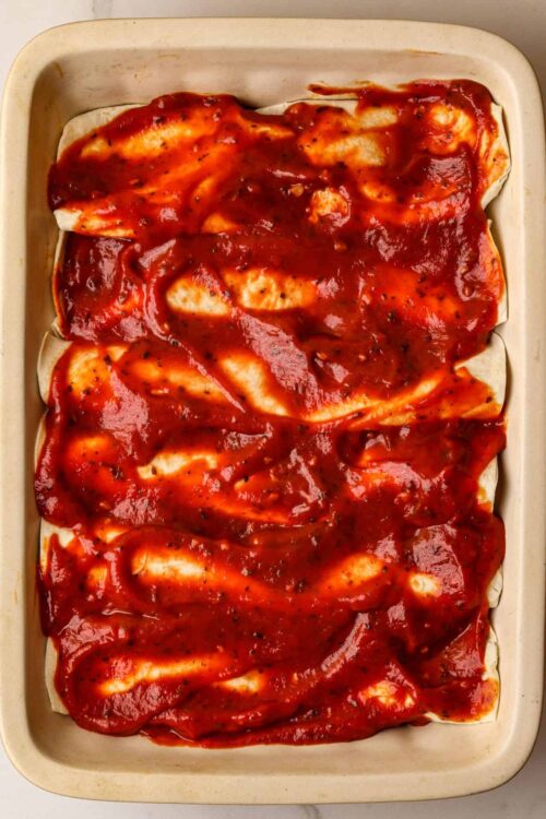 Savory stuffed pasta rolls with marinara sauce in a baking dish.