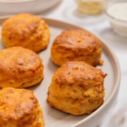 Savory chicken meatballs on white ceramic plate with dipping sauces in background.