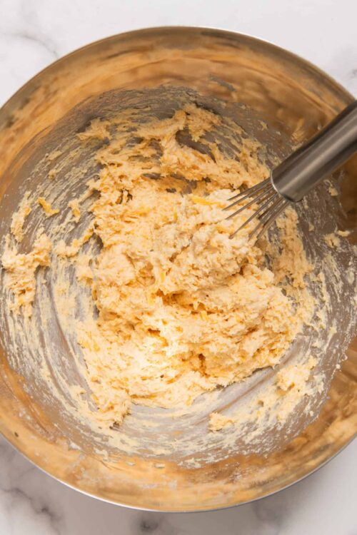 Creamy cookie dough mixture in a stainless steel mixing bowl with a handheld mixer.