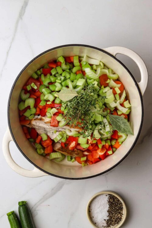 Chopped celery, carrots, and herbs in a pot for homemade soup or stew.