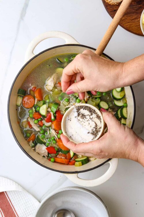 Fresh vegetable chicken soup with herbs in a pot.