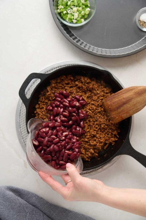 Cooked ground beef with red kidney beans in a skillet, prepping for a hearty recipe.