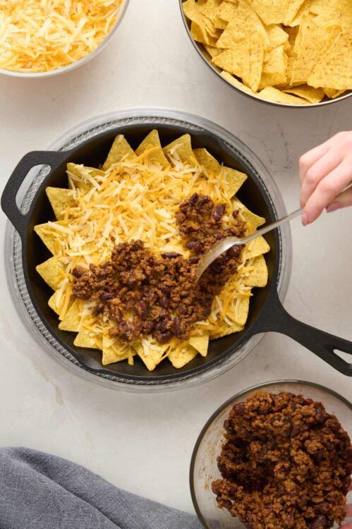 Cheese and taco meat layered in a cast iron skillet for nachos or casserole.
